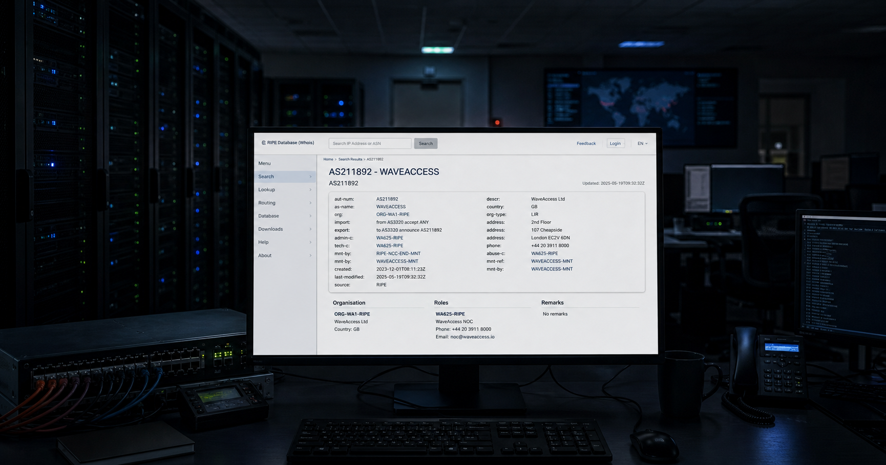 A network operations center console showing the WaveAccess registry record, with dark server racks in the background.