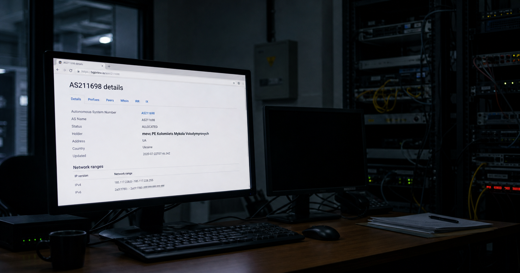 A dimly lit network operations center with a monitor showing a registry page for AS211698, disconnected cables.