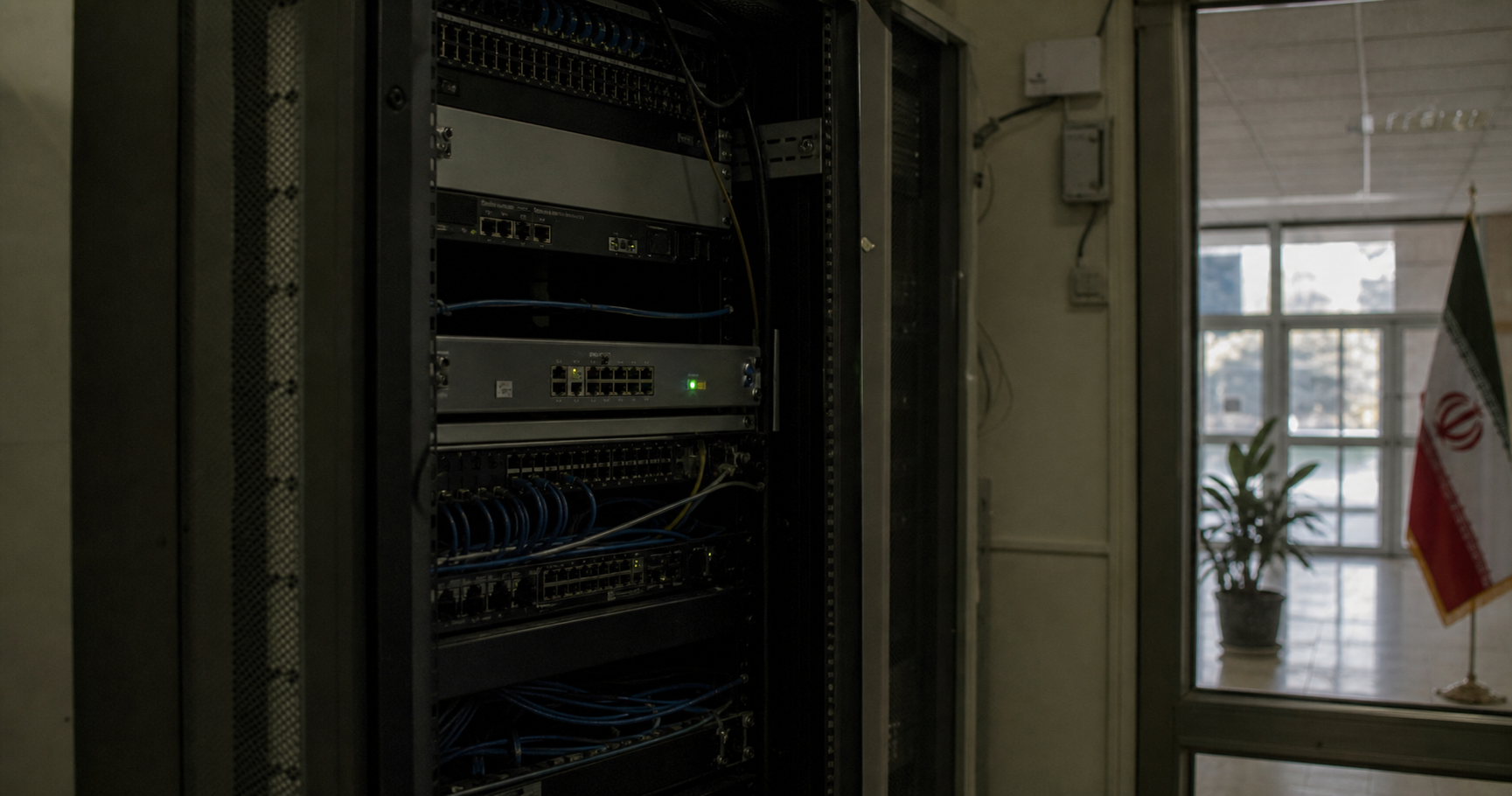 Dormant network equipment in a university setting with a map of Iran in the background, symbolizing the unannounced AS211491.