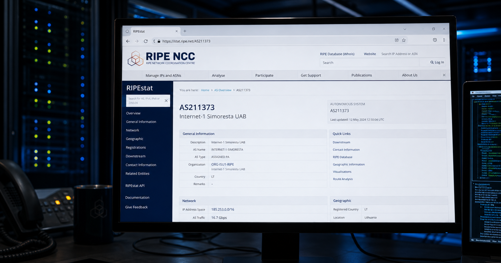 A network operations center monitor displays a RIPE NCC interface with AS211373 registry details, in a dimly lit server room.