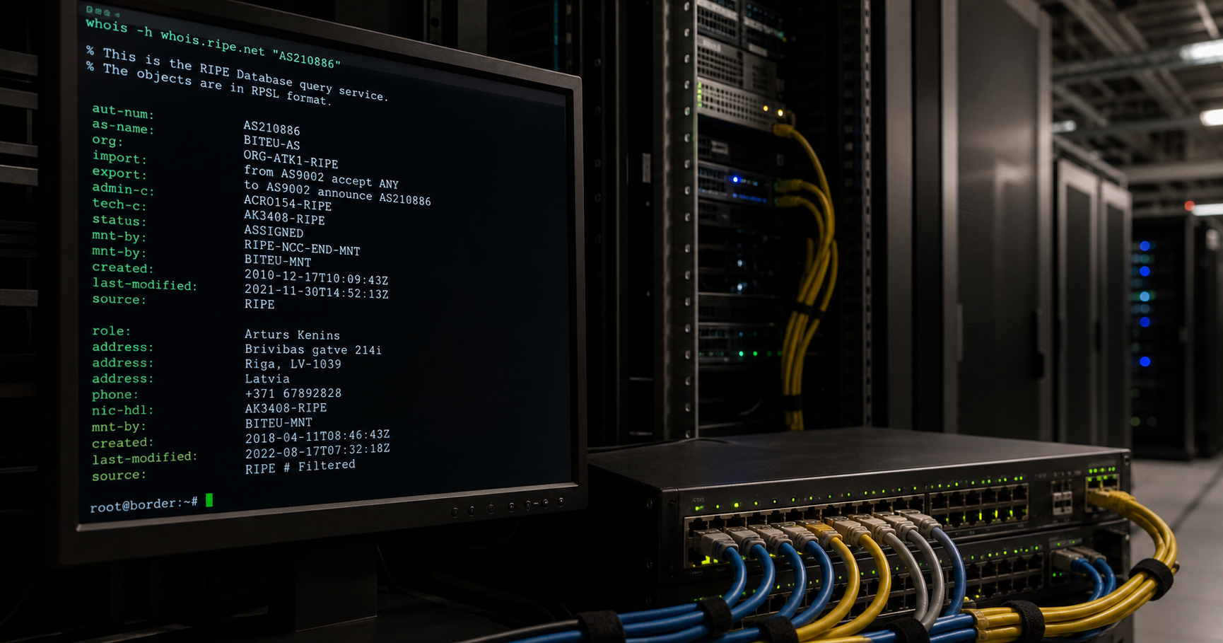 A dimly lit server room with a rack-mounted monitor displaying a WHOIS query for ASN 210886, highlighting the technical contact field.