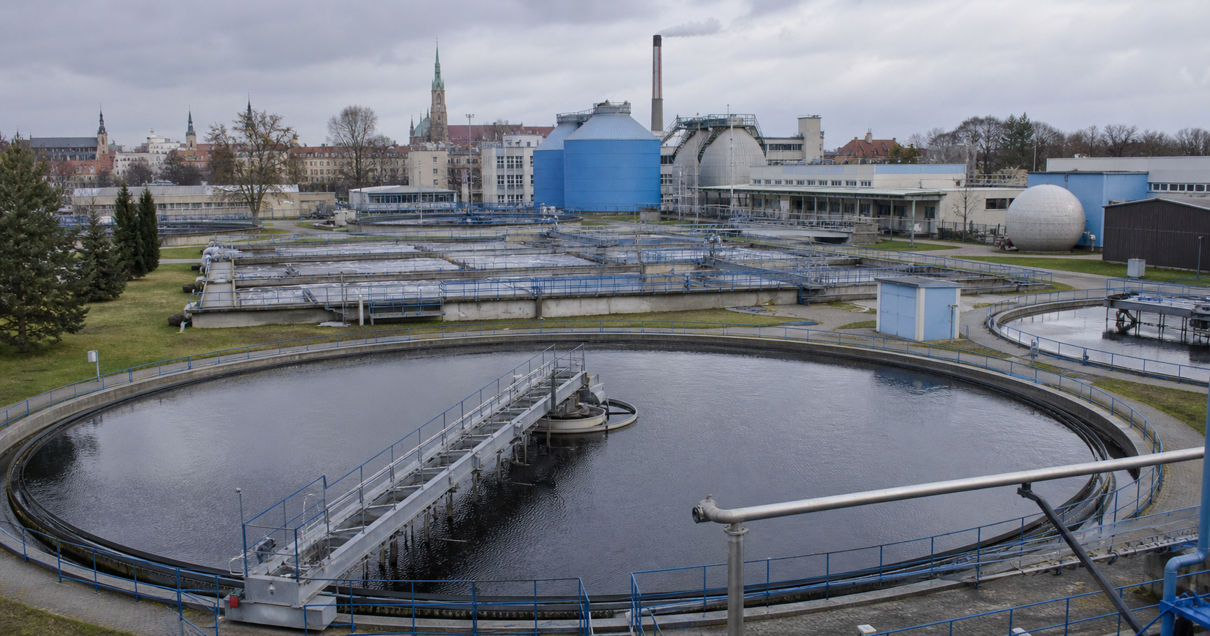 MPWiK Wrocław water treatment facility with workers in orange vests inspecting aeration basins under daylight.