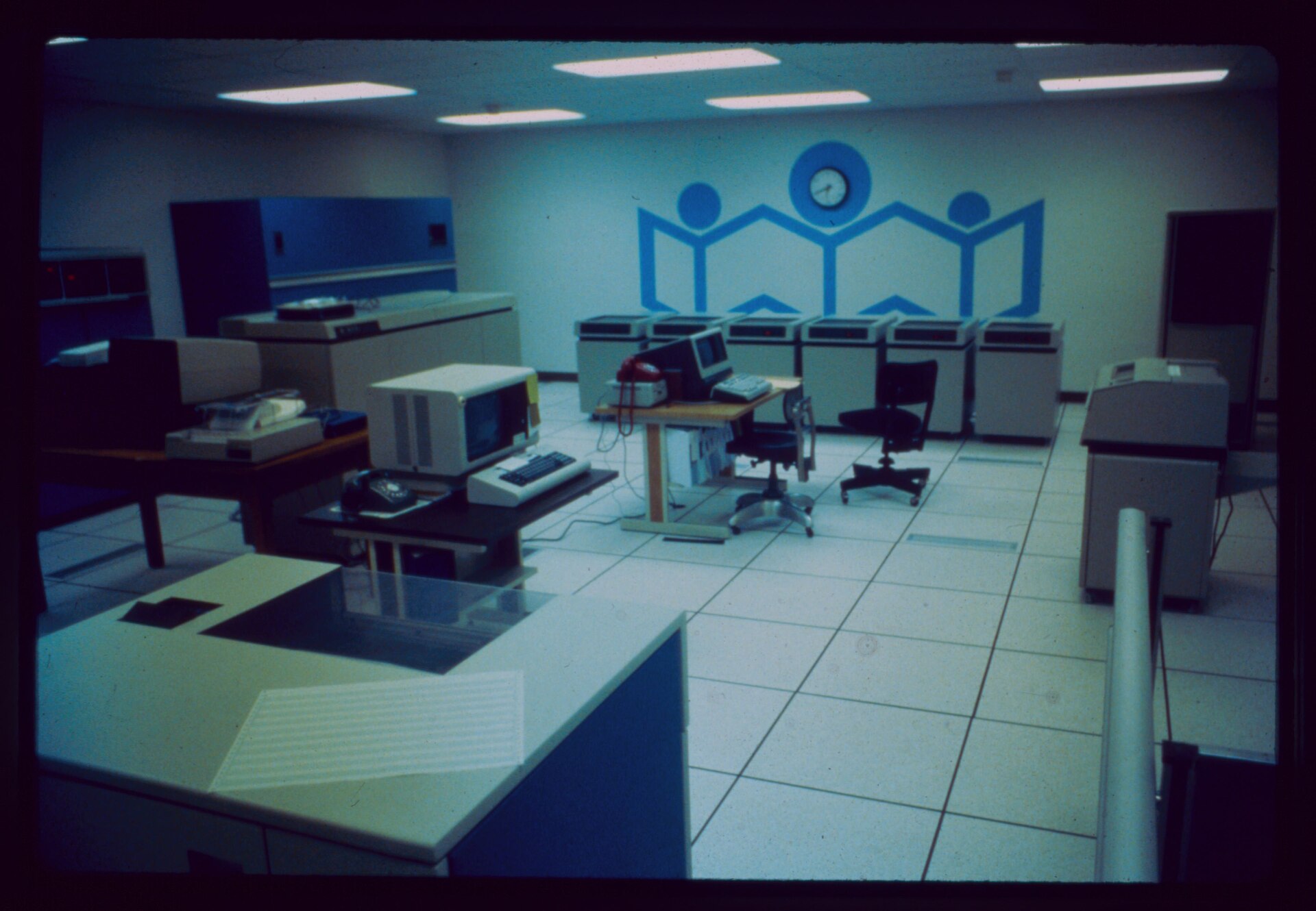 A historical server and data communications room with computer consoles and raised-floor equipment.