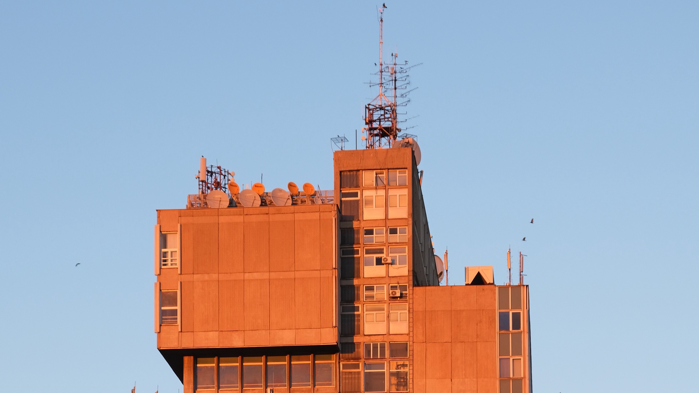 Upper levels and rooftop antennas of the Telekom Srbija TK centre in Belgrade in warm evening light